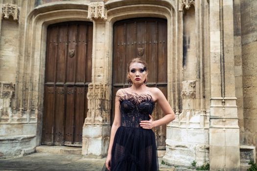 A stylish bride in a black wedding dress in the ancient French city of Avignon. A model in a black dress.