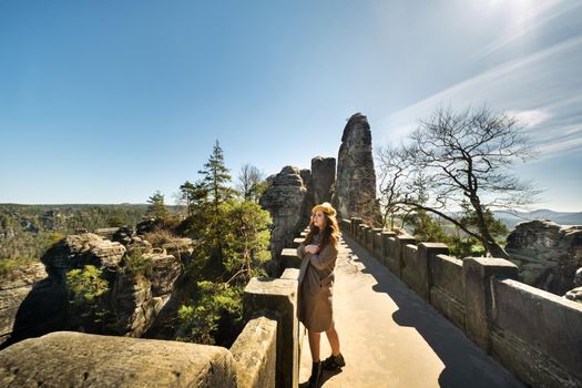 a girl in a grey coat and hat on a bridge in Saxon Switzerland, Germany, Bastei