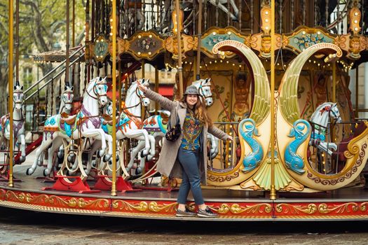 A girl in a coat on the city carousel in Avignon.France.