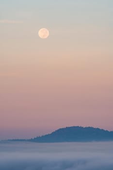 Full moon falling And the mist in the morning time. The color orange sky reflects the sun's rays.