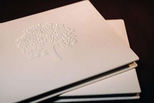 Composition of photo books in natural white leather of different sizes. The white paper on a dark background