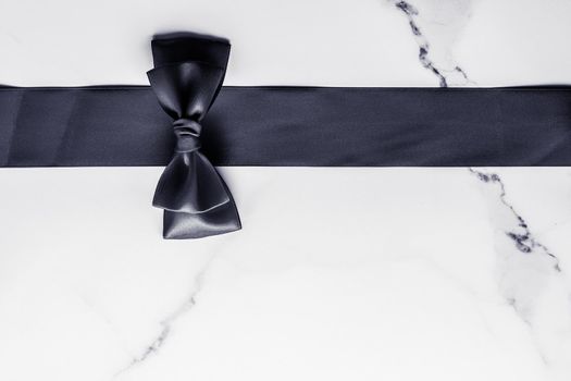 Holiday gift, decoration and sale promotion concept - Black silk ribbon and bow on marble background, flatlay