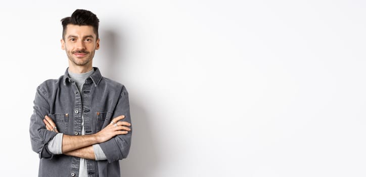 Confident handsome guy in casual outfit cross arms on chest, smiling pleased, standing professional on white background.