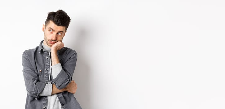 Gloomy thoughtful man looking aside, thinking or space out, staring at empty space bored, standing on white background.