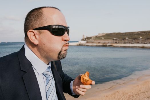 Male persimmon park. Hipster millennial man in a tie and jacket bites off a persimmon while sitting on a park bench in slow motion Young business people eat golden persimmons at lunchtime