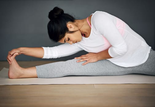 Yoga is a great way to stay fit and focused. a young woman stretching during her yoga routine