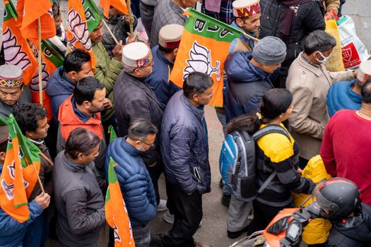 Delhi, India - circa 2022: aerial drone shot crowd people with saffron flags of BJP protesting or celebrating victory in hill station manali standing in circle with leader