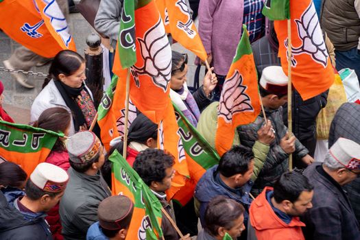 Delhi, India - circa 2022: aerial drone shot crowd people with saffron flags of BJP protesting or celebrating victory in hill station manali standing in circle with leader