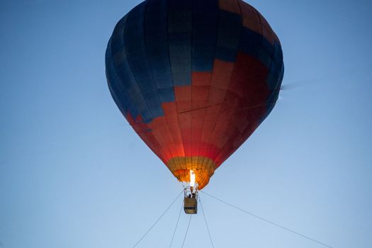 Hot air balloon with fire heating air in wicker basket with himalaya mountains in background showing this adventure in kullu manali valley India