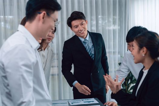 Harmony in office concept as business people analyzing dashboard paper together in workplace. Young colleagues give ideas at manager desk for discussion or strategy planning about project.