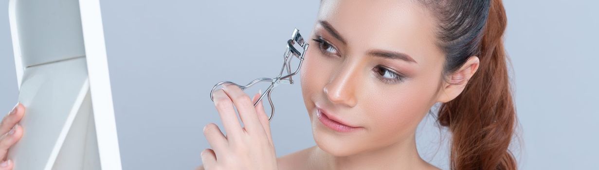 Closeup glamorous facial makeup, beautiful woman with perfect smooth cosmetic clean skin correct eyelash curler with metal mechanic beauty accessory in isolated background.