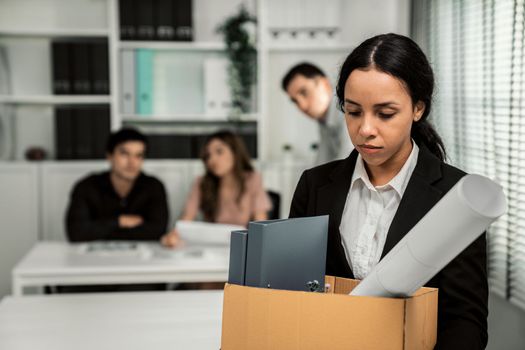 Depressed and disappointed employee packing her belongings after being fired for not being competent. Gossiped by her colleagues behind his back. Layoff due to economic depression.