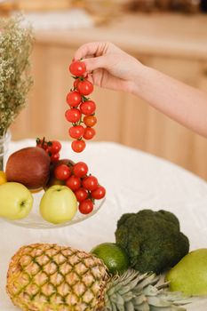 close-up of vegetables, fruits on the kitchen table. cooking.The hostess holds small tomatoes in her hand.