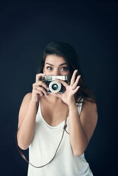 Theres something good in every day. a beautiful young holding a camera against a dark background