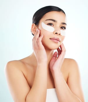 These wrinkles wont have their way. Studio shot of an attractive young woman using under eye patches against a light background