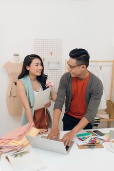 Talking about new fashion design. Beautiful young woman talking with her partner while working together in the workshop