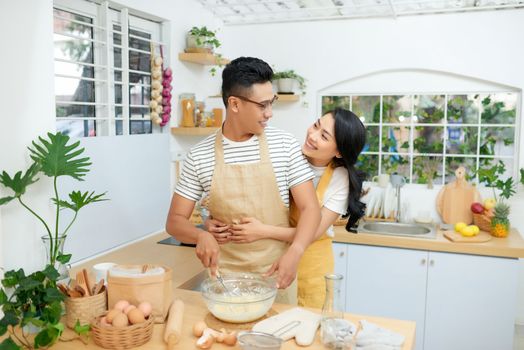 Couple cooking bakery in kitchen room, Young asian man and woman together making cake and bread with egg,