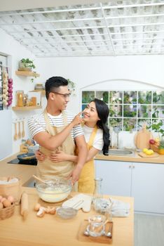 Young couple making dough in kitchen together