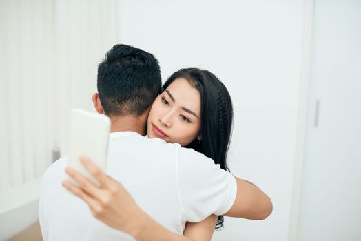 Young couple in the bedroom. An attractive woman is checking incoming messages in the morning