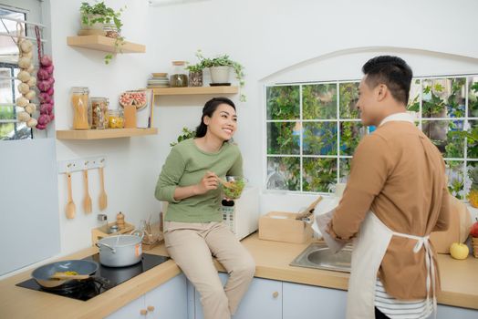 Loving woman feeding man while cooking dinner at kitchen.