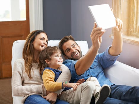 Lets take a family selfie. a happy family using a digital tablet to take a selfie