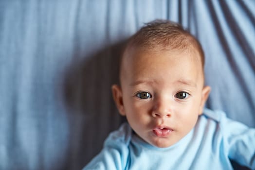 The sweetest face in the world. Portrait of an adorable baby boy laying on the bed at home