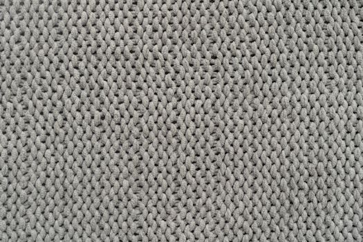 Knitted gray background. Close-up of a knitted blanket. Wavy folds material. Knitted warm grey sweater or scarf. Banner, copy space