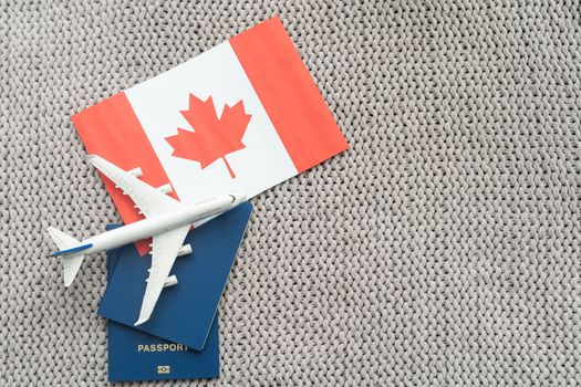 Flag of Canada with passport and toy airplane. Flight travel concep.