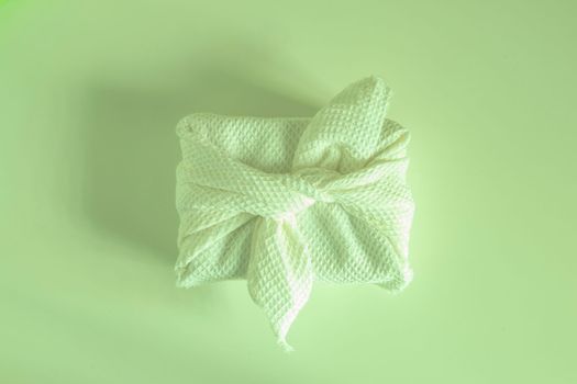 Furoshiki is a Japanese gift wrapping fabric that is traditionally used in Asia. environmental gifts. green background.
