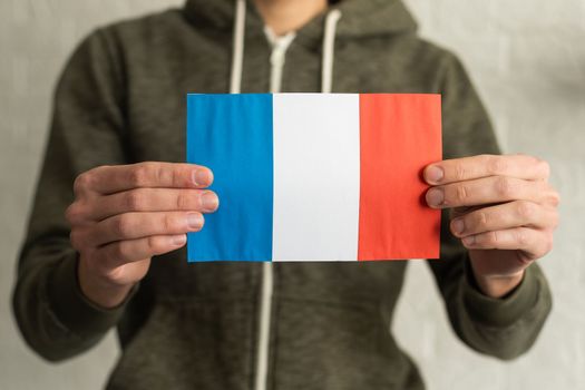 Small paper flag of France in hand.