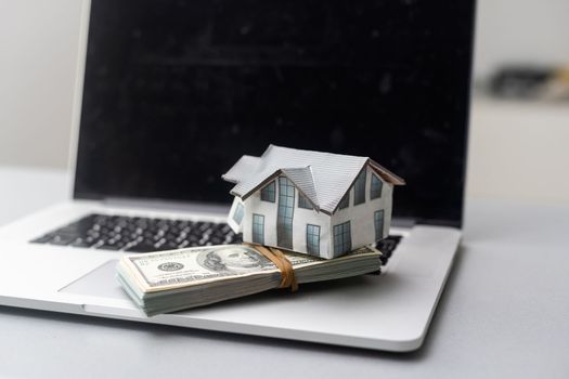 house model with dollar banknotes on laptop keyboard.