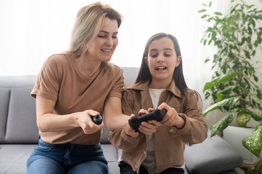 Photo of domestic funny blond lady mom daughter sitting comfy couch hold joystick playing video games stay home safety quarantine spend weekend together best friends living room indoors