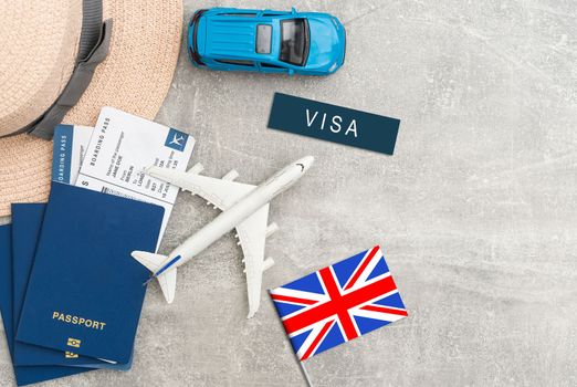 Flag of United Kingdom with passport and toy airplane on wooden background. Flight travel concept.