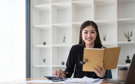 Asian businesswoman meeting at the office, taking notes and using a tablet at the office...