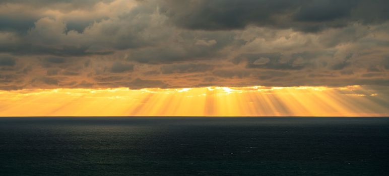 Sunbeams by the sea of clouds baner. Seascape with dark clouds and the rays of the sun from them