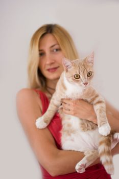 Beautiful young blonde woman holging her ginger cat.