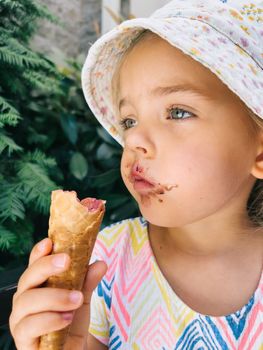 Little girl holding a waffle cone with ice cream in her hand. High quality photo