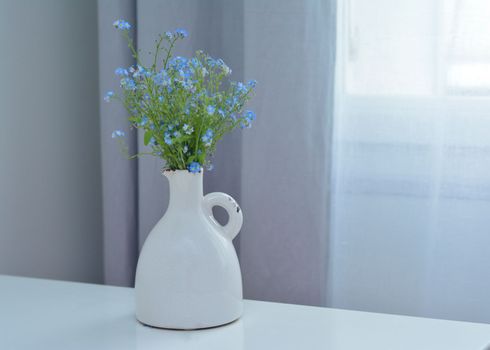 A bouquet of blue forget-me-nots in a white vintage vase Copy space