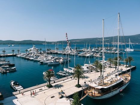 Sailing yacht moored at a tiled pier with potted palm trees. High quality photo