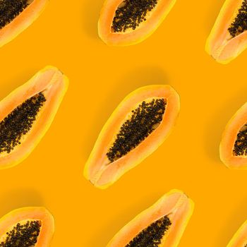 Fresh ripe papaya seamless pattern on orange background. Tropical abstract background. Top view. Creative design, minimal flat lay concept. Trend tropical fruit food background pattern