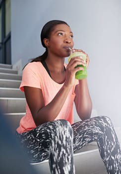 Fitness refreshment. an attractive young woman drinking juice while exercising outdoors