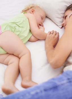 Shes always close to her baby. A young mother lying next to her sleeping baby on the bed