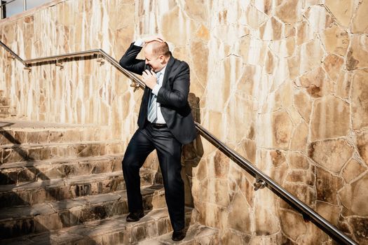 Portrait of a senior professional man in a suit with various problems. A middle-aged businessman with a briefcase descends the stairs.