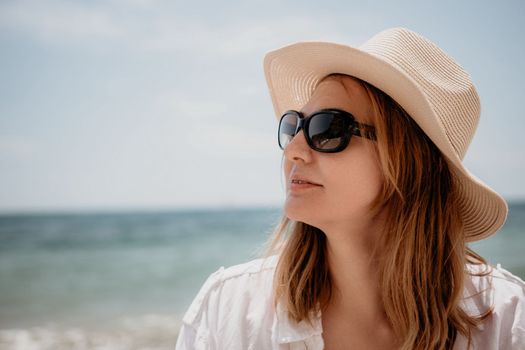 Young woman in red bikini on Beach. Blonde in sunglasses on pebble beach enjoying sun. Happy lady in one piece red swimsuit relaxing and sunbathing by turquoise sea ocean on hot summer day. Close up,