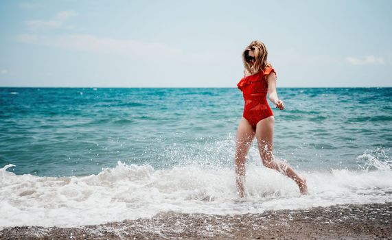 Young happy woman walks carefree on the seaside. Happy lady in red bikini. Portrait beautiful young woman relax smile around beach sea ocean in holiday vacation travel trip.