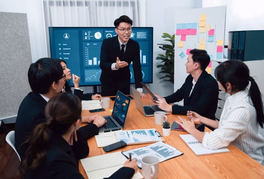 Confidence and asian businessman give presentation on financial analyzed by business intelligence in dashboard report to other people in board room meeting to promote harmony in workplace.