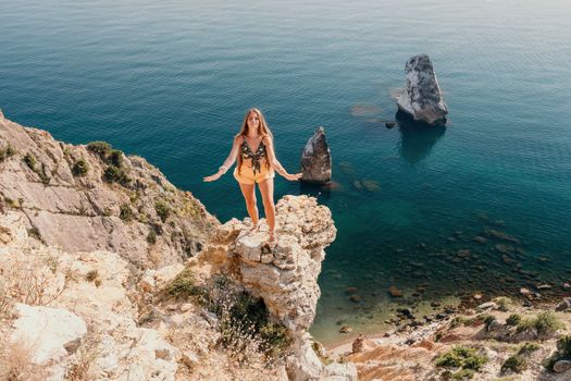 Woman travel sea. Happy tourist taking picture outdoors for memories. Woman traveler looks at the edge of the cliff on the sea bay of mountains, sharing travel adventure journey.