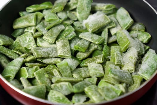 Frozen green beans in a pan ready for cooking. Vegetable preservation. Selective focus