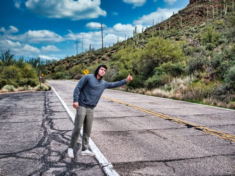 Handsome young man, a hitchhiker waiting for car on roadside in city, wearing hoodie sweater in Arizona, USA