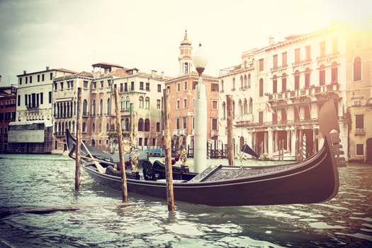 Vintage style cityscape of Venice with traditional gondola boat moored in channel water against typical architecture of residential buildings